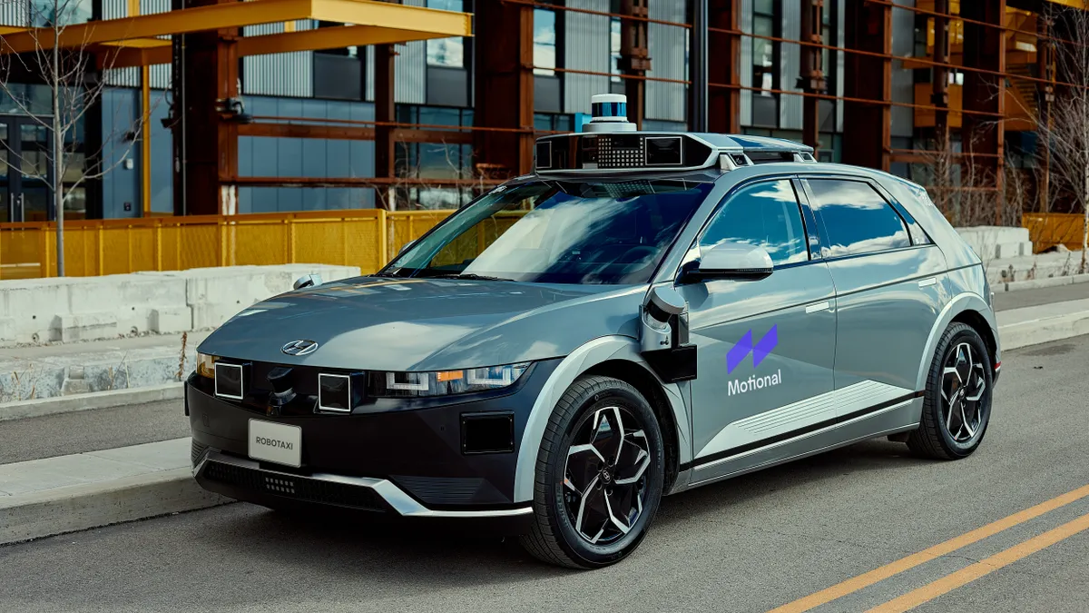 A Hyundai Ioniq 5 electric SUV test vehicle on the road in downtown Pittsburgh with building in the background.