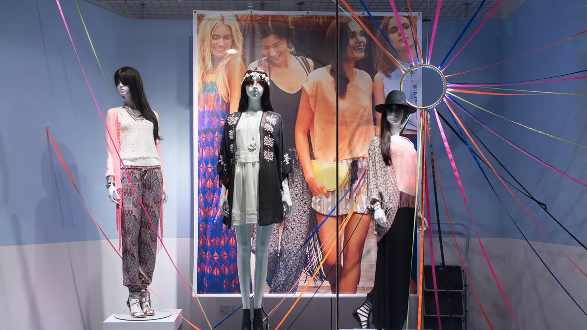 Three mannequins are pictured in a New Look store window display.