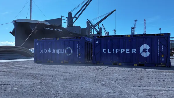 A set of blue collapsible containers with an ocean vessel in the background.