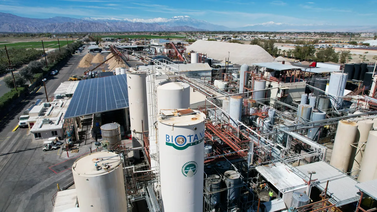 Aerial view of industrial facility with solar panels, mountains in background