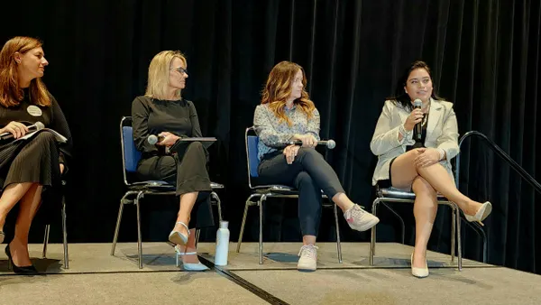 Four women sitting in chairs next to each other, and each holding their own microphone.
