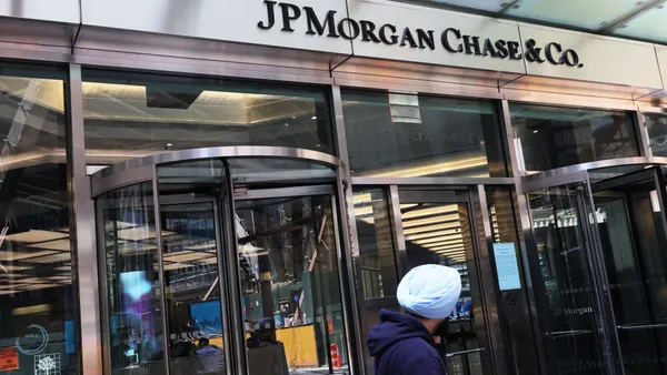 An entrance to a Madison Avenue JPMorgan Chase building is shown, with revolving doors and a person walking in the foreground.