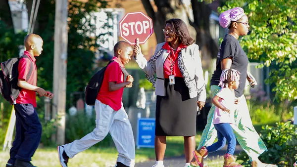 Topeka Public Schools Superintendent Tiffany Anderson stands in a crosswalk with a stop sign as students pass by on their way to school.