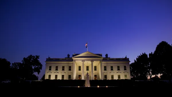 The north facade of the White House is seen partially illuminated at night