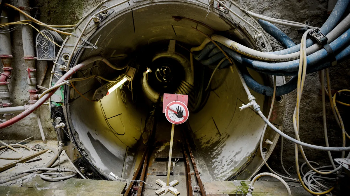 A do not enter sign stands in front of a concrete tunnel at the construction site.