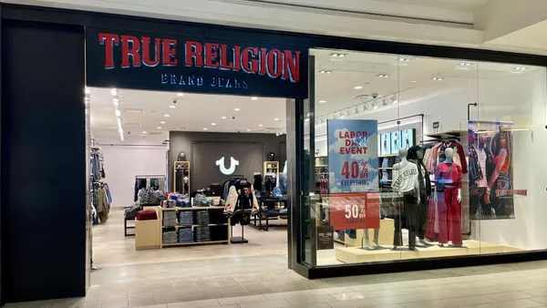 A True Religion storefront in Atlanta's Cumberland Mall with the company's red logo on a dark background