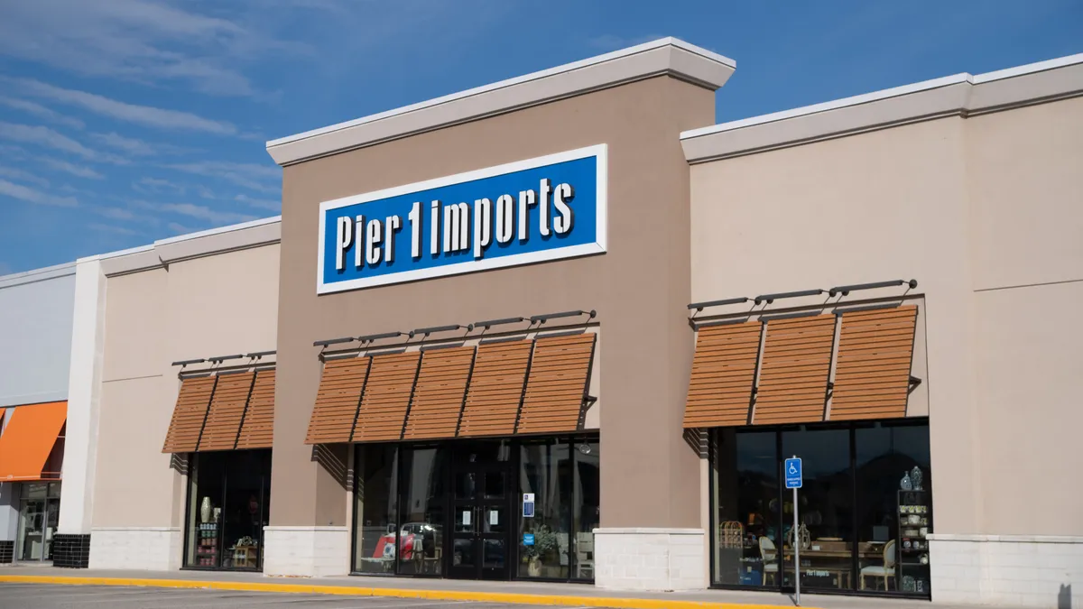 A store with blue and white signage, with a blue sky and whispy clouds above and a row of awnings below.