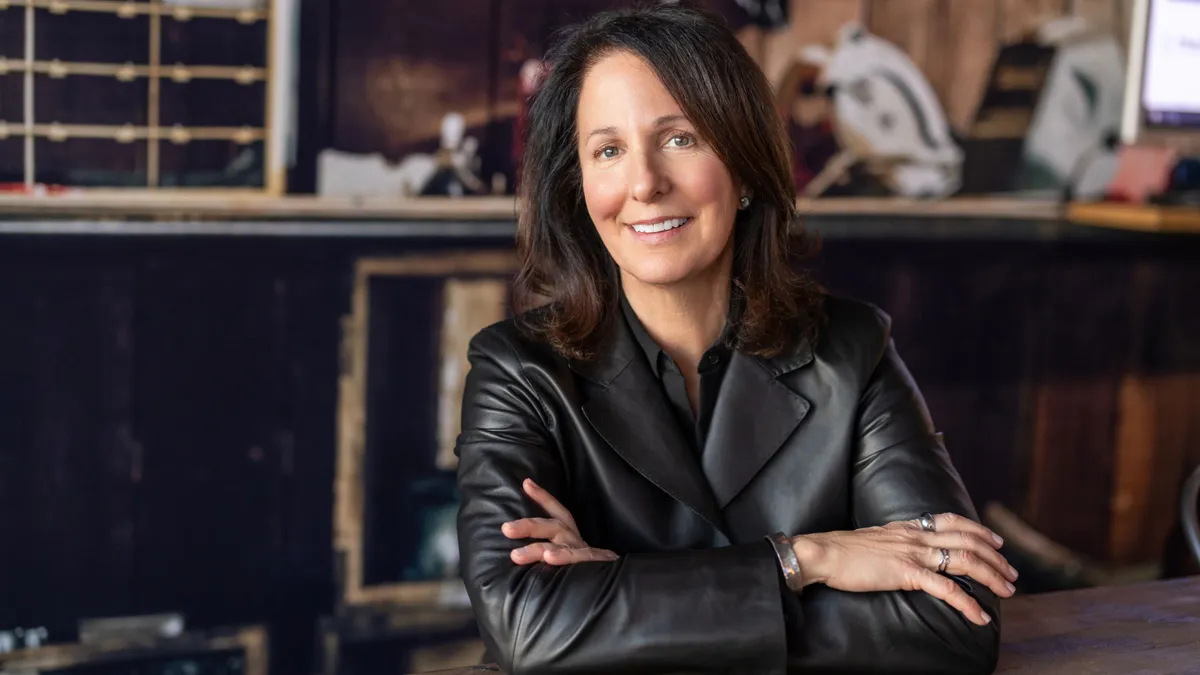 Advertising executive Kristi Argyilan, wearing a black leather jacket, sits with her arms crossed at a dark wood table