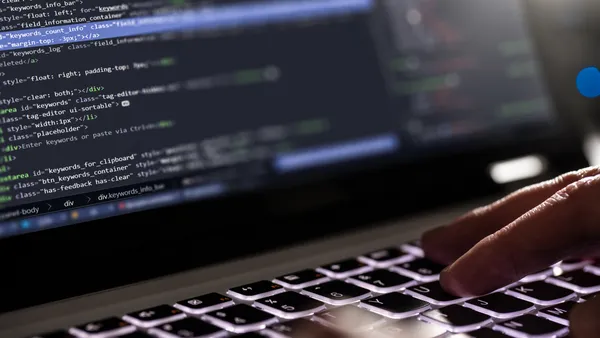 closeup of hands on a keyboard, software code featured in the screen