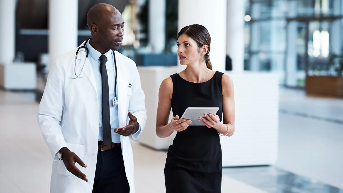 Male doctor and young businesswoman looking over a tablet in the hospital