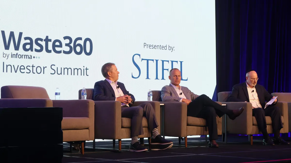 Three people sit on a stage. Behind them, a screen reads "Waste360 by Informa, Investor Summit. Presented by: Stifel."