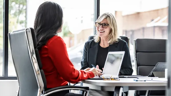 Two professionals talking in a meeting room.