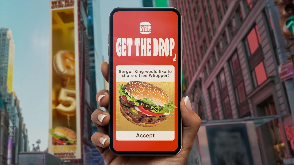 A hand holds a smartphone displaying a code for a free whopper in times square.