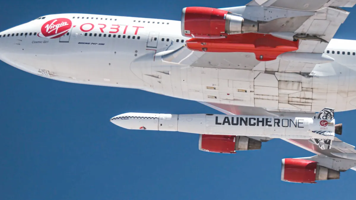 Virgin Orbit's mainly white with red wings Cosmic Girl aircraft releases the white LauncherOne rocket mid-air on a clear and sunny day.