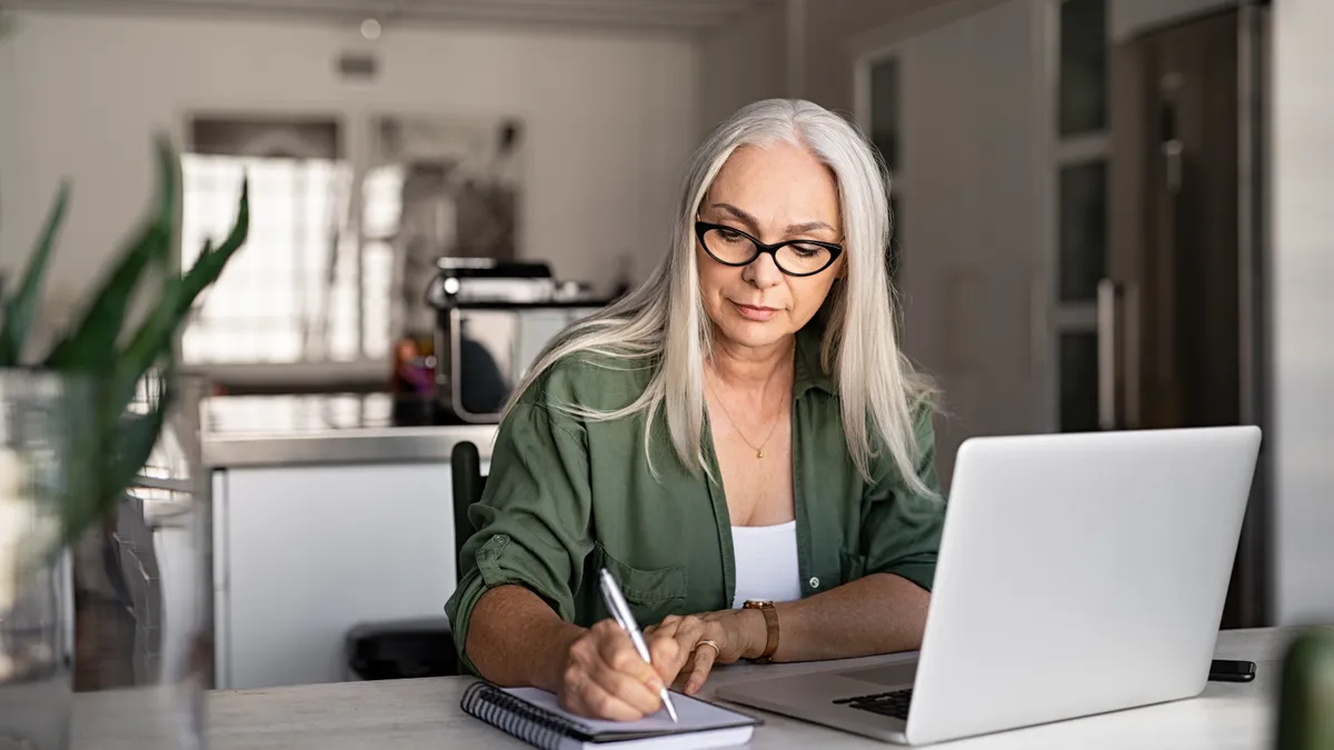 An older woman types on a laptop