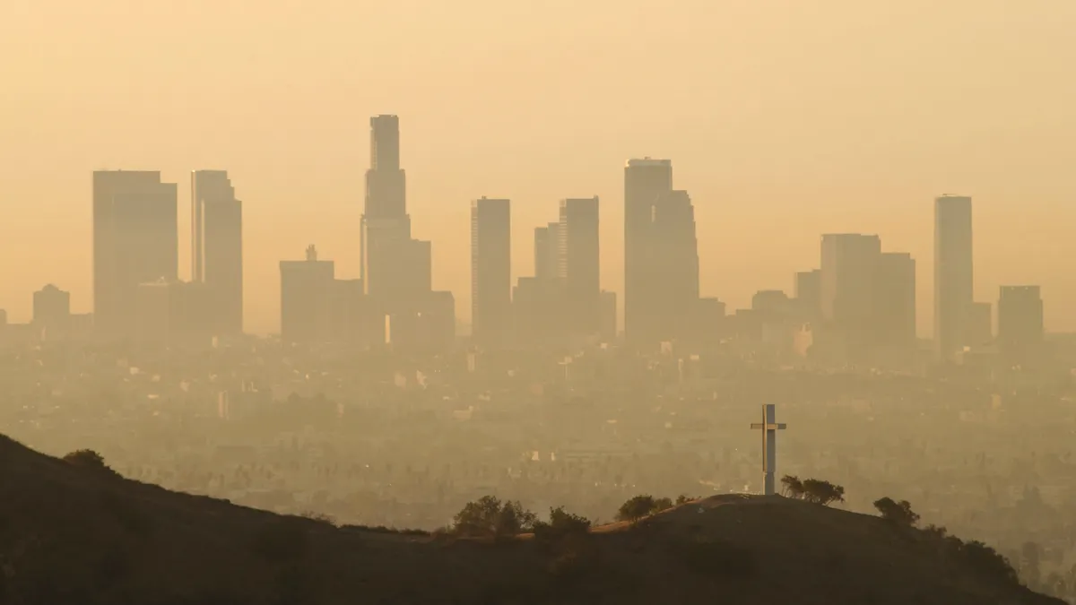 Tall buildings seen at a distance shrouded in smog.
