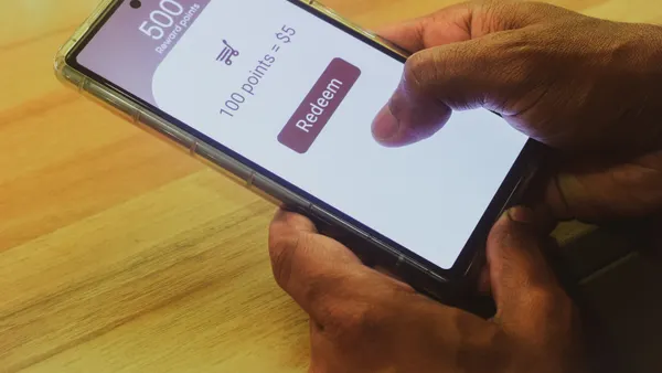 A close up of a person holding a phone featuring rewards points and the ability to redeem them.