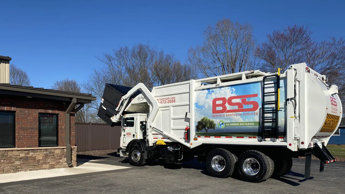 A waste truck in a parking lot with Benfield Sanitation Services branding.