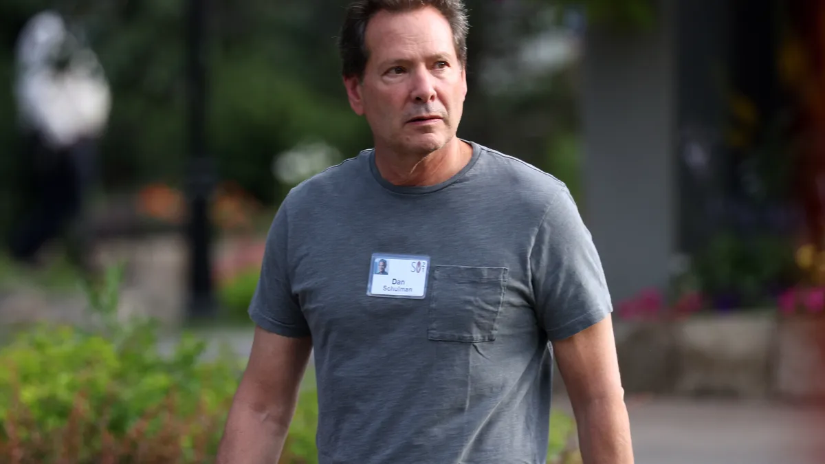 Schulman walking outside with a name tag on his chest.