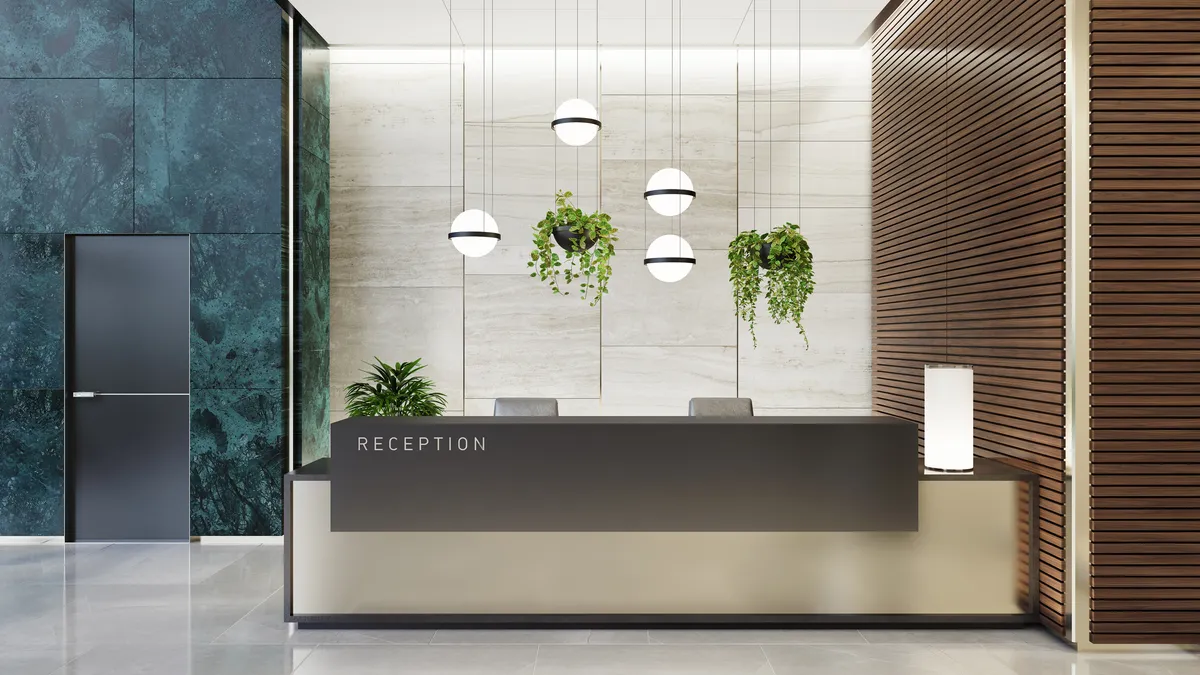 A modern and luxurious office lobby interior with elevators and stairs. The lobby features a long reception desk, green marble tiles on the walls.