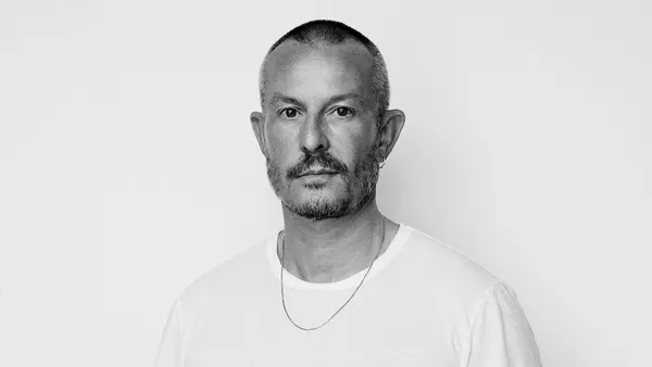 Black and white photo of a person with facial hair wearing a white T-shirt.