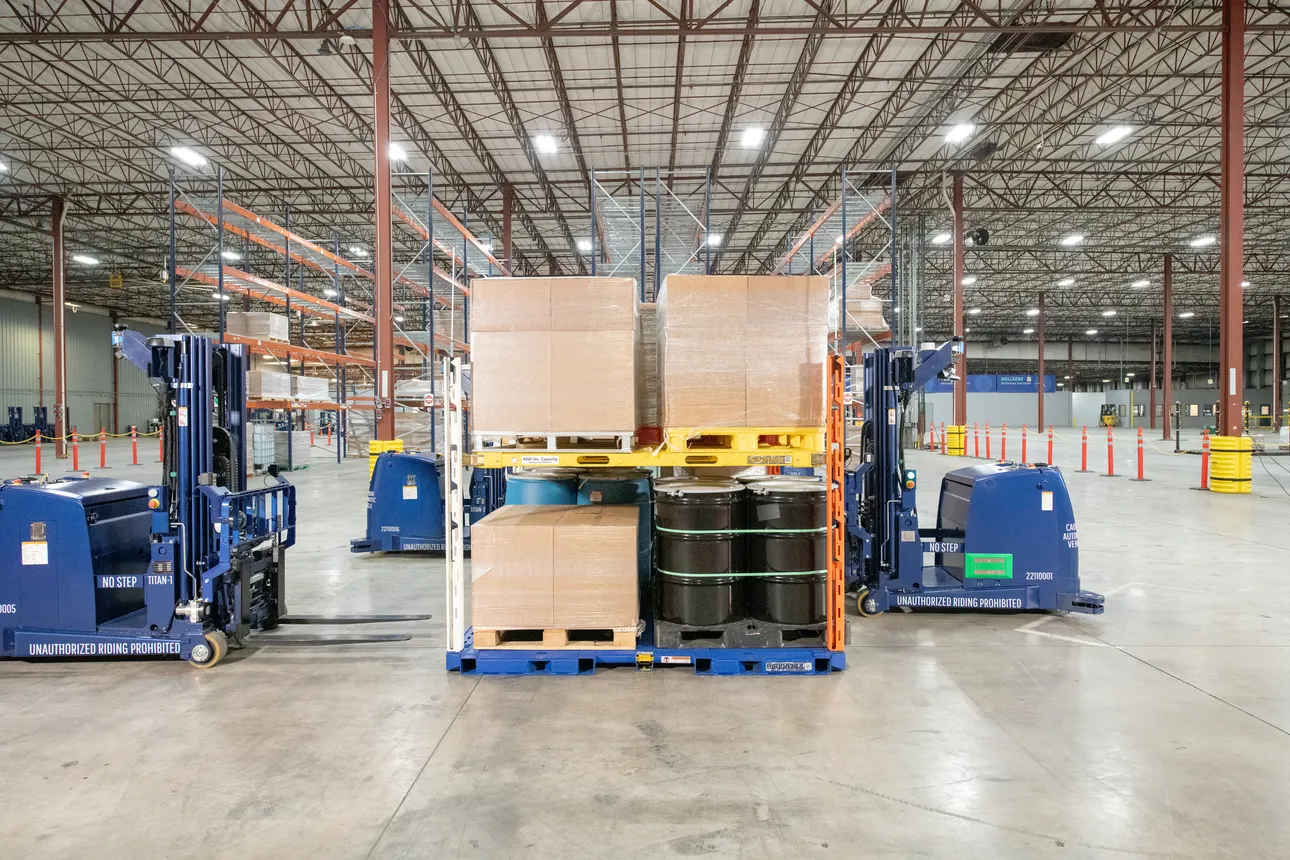 ArcBest's autonomous forklifts simultaneously unload a blue platform removed from the floor of a trailer, rather than having to wait their turn.