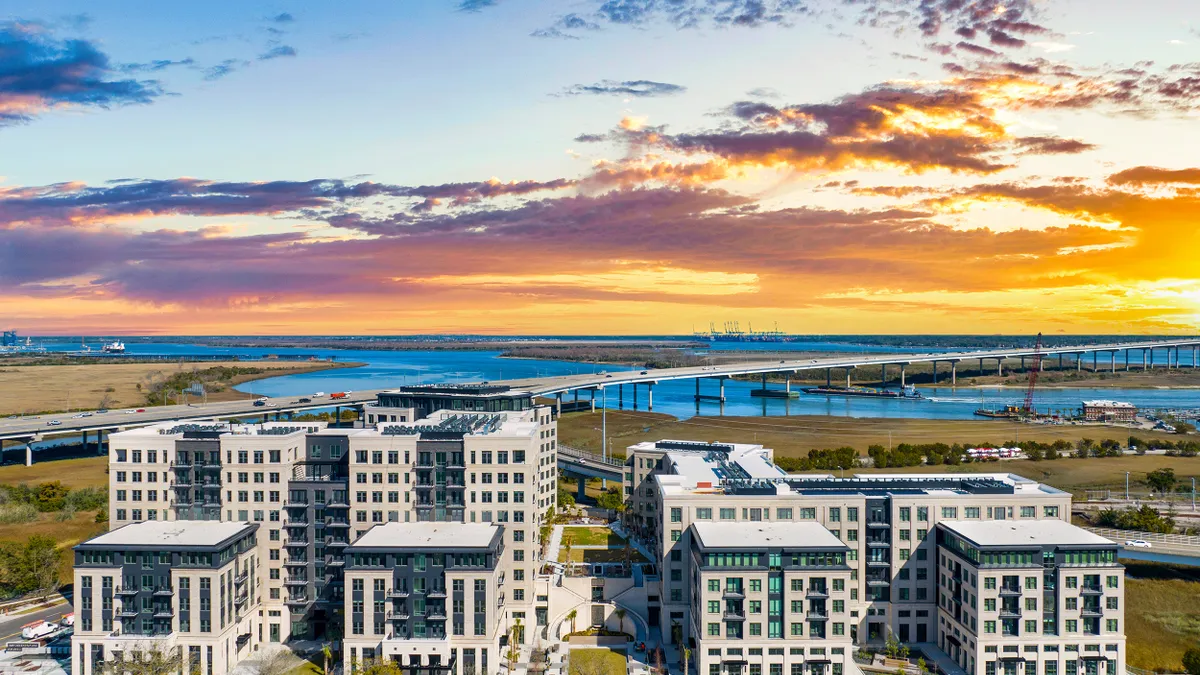 Picture of new light-colored apartments with a highway and water in the background.