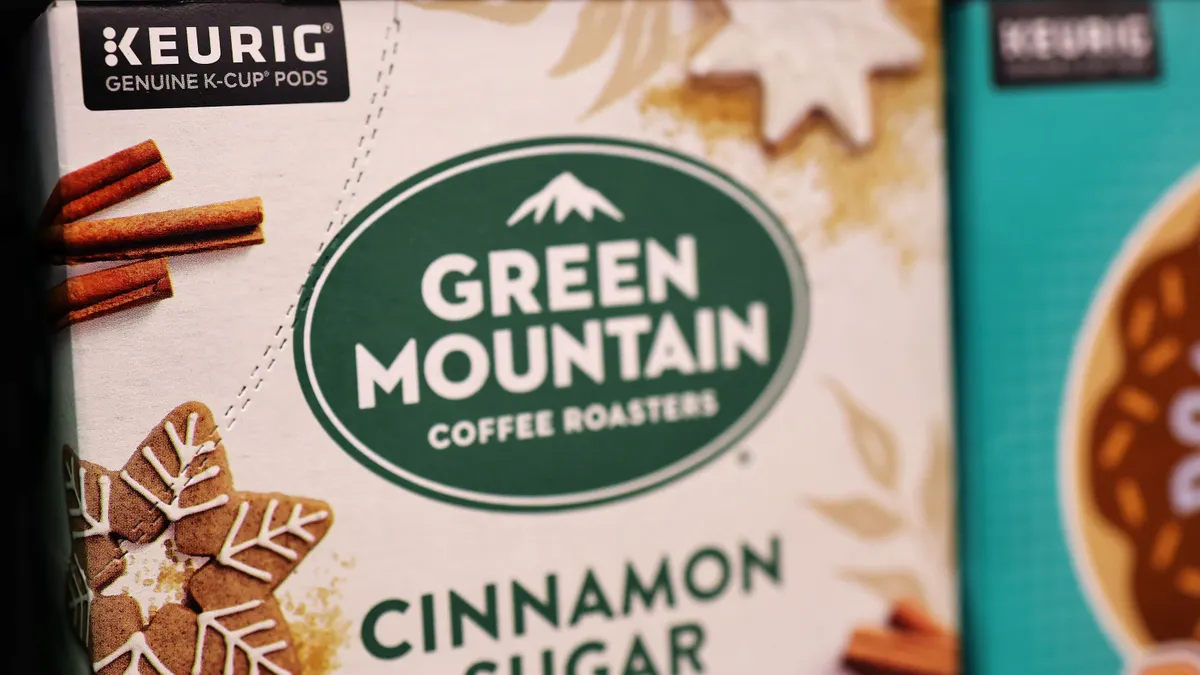 Boxes of Green Mountain Keurig coffee K-Cup pods displayed on a store shelf. The box lable reads "Keurig Genuine K-Cup Pods Green Mountain Coffee Roasters Cinnamon Sugar Cookie"