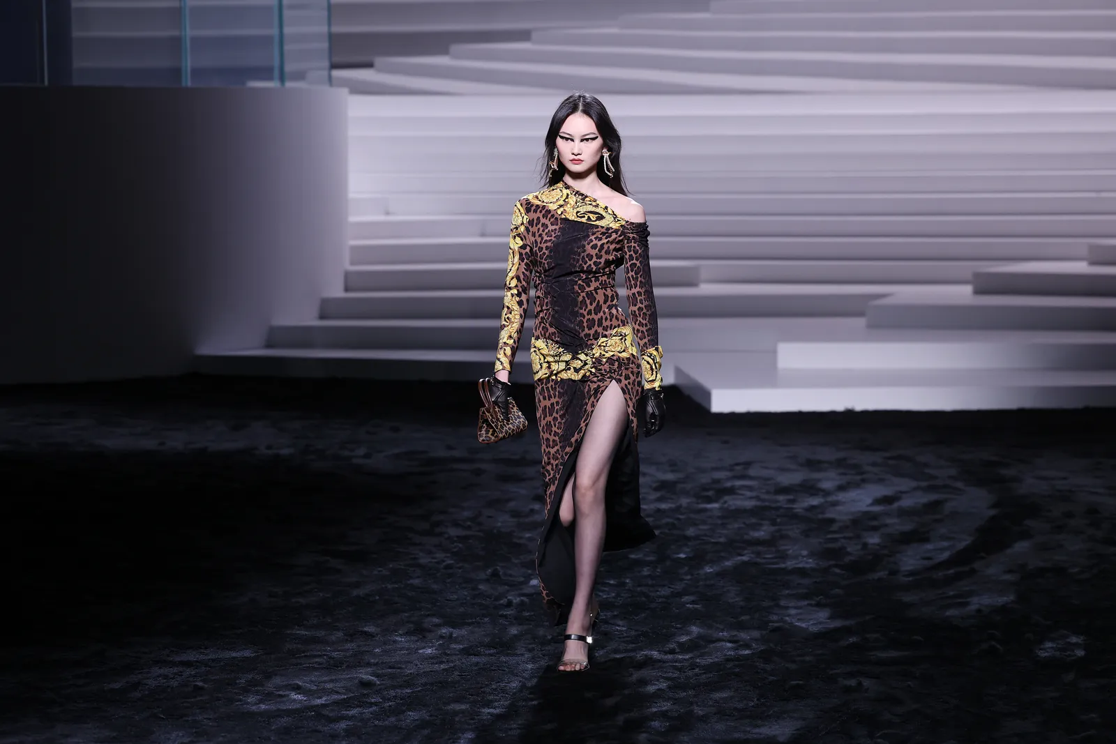 A model in a leopard print dress on a runway.