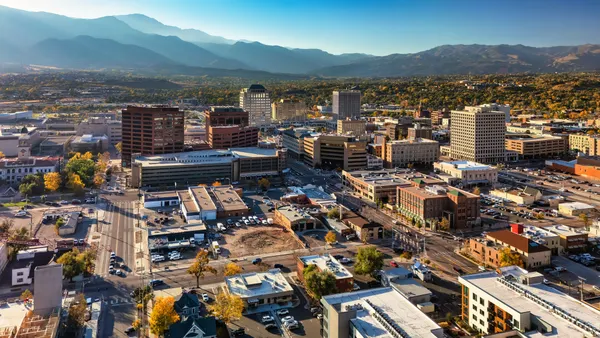 A skyshot of a city with mountains in the background in the afternoon light.