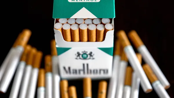 A photo of a pack of Marlboro menthol cigarettes, with several cigarettes loose on a black surface around it.