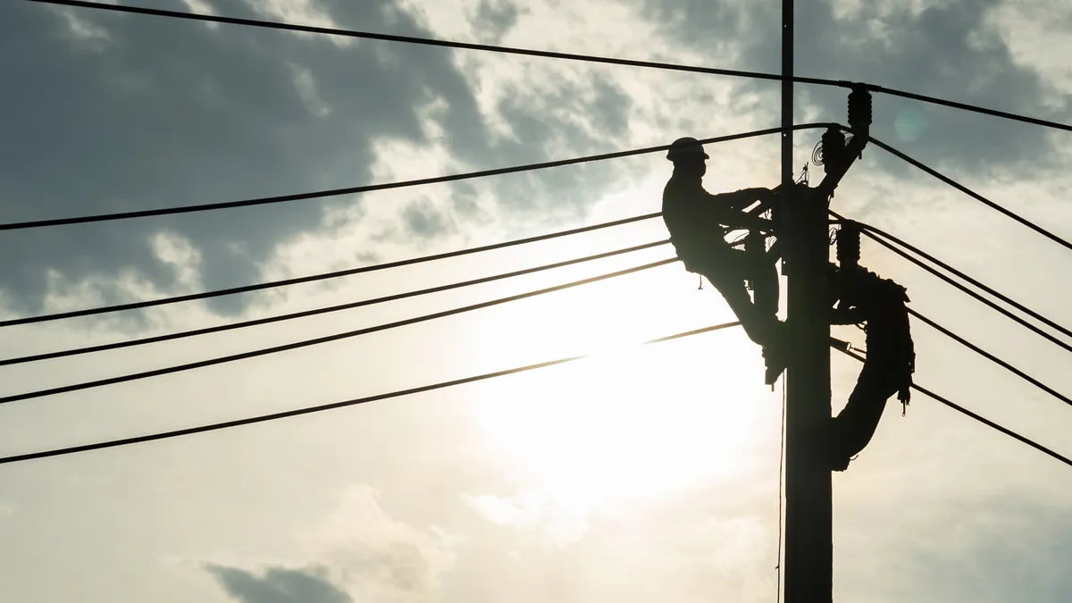 Electrician worker climbing electric power pole to repair the damaged power cable line problems after the storm.