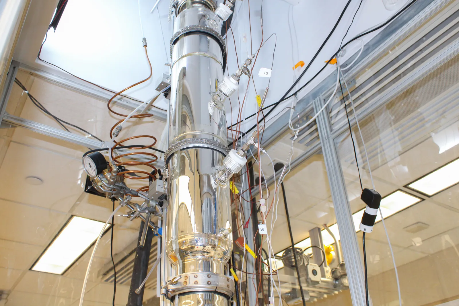 A tall bioreactor spans multiple floors in a biotechnology lab.