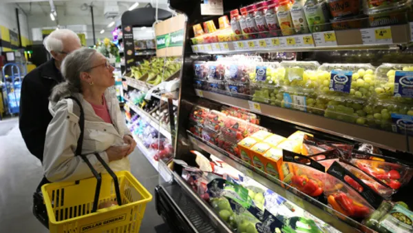 Two people shopping in the produce section at Dollar General.