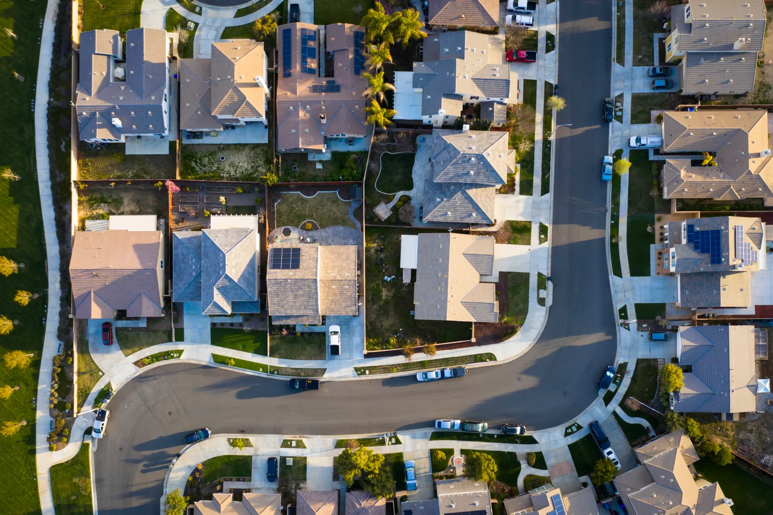 Aerial view of rooftops in a suburban neighborhood. A street curves through the houses.