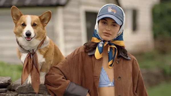 A person in a blue and white striped outfit stands next to a dog.
