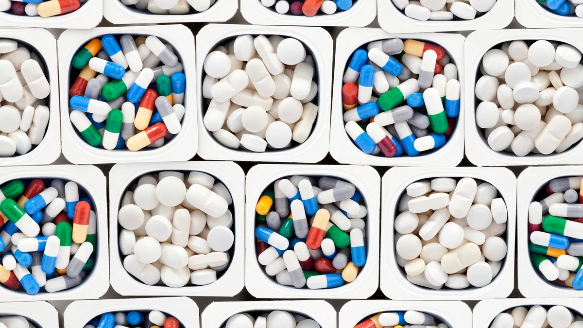 Bunches of pills in varied colors are organized in containers.