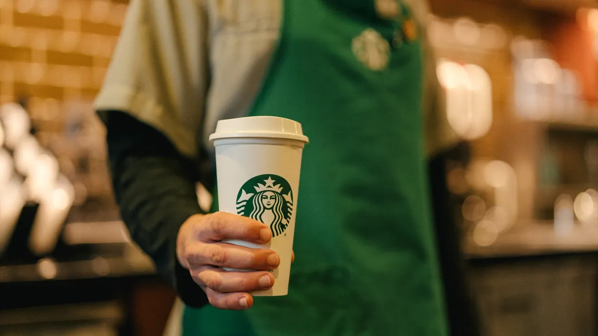 A Starbucks worker holds a beverage.