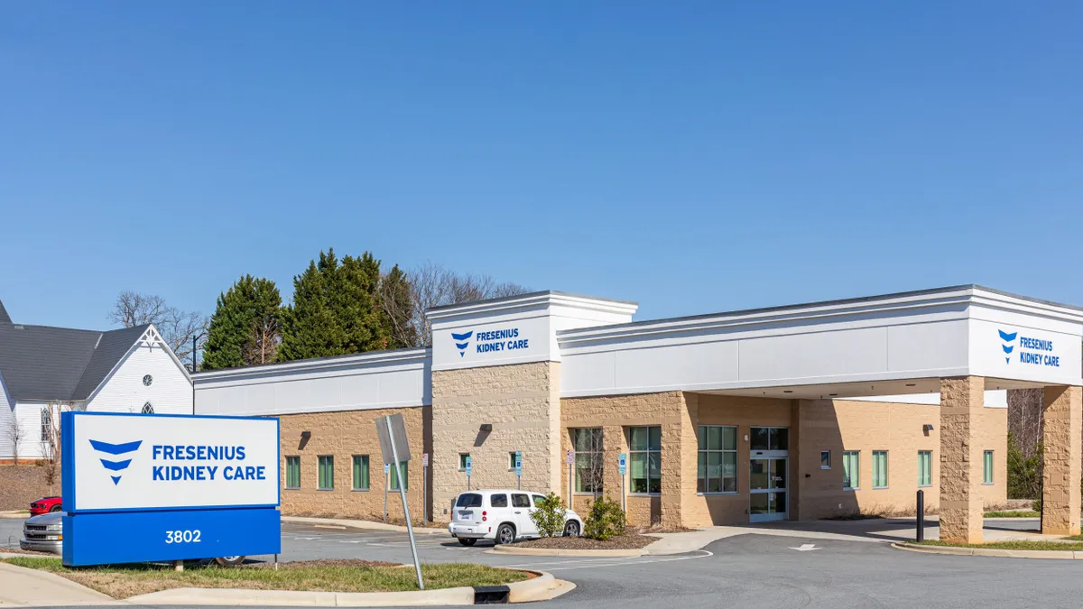 A picture of a Fresenius Medical Care building, company sign and parking lot on a sunny day.