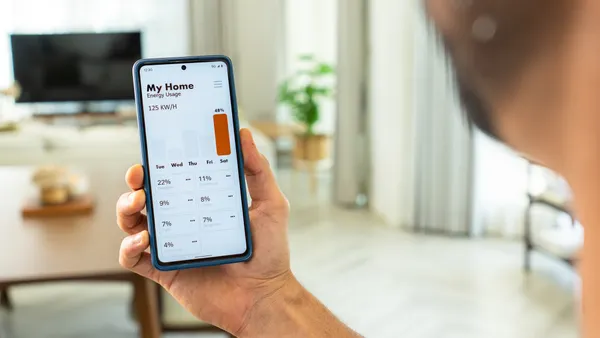 A handsome mid-adult man watching a smartphone to track day and month energy usage, underscoring the proactive way to energy conservation in addressing global warming issues