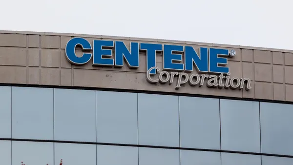 A modern office building facade with blue-tinted windows and a curved design. A sign near the roof reads “Centene Corporation” in blue and gray lettering.