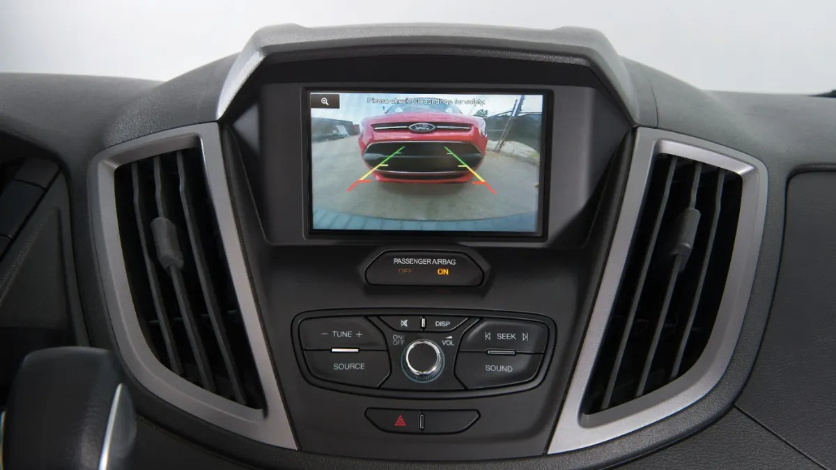 The center display in a 2017 Ford Transit van showing a red vehicle on the screen.