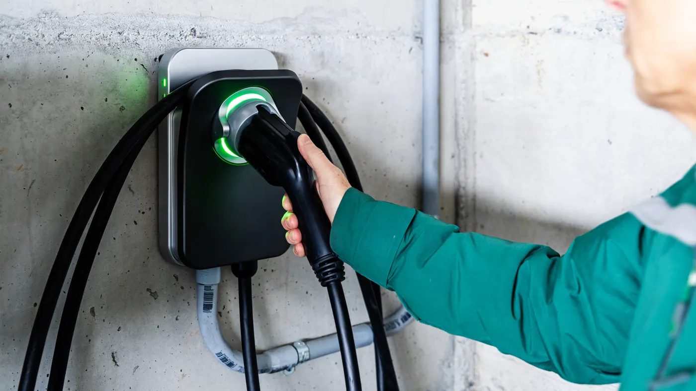 A man holds an electric vehicle charger.