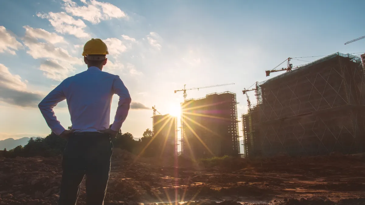 a man in a hard hat looks over a construction site as the sun goes down