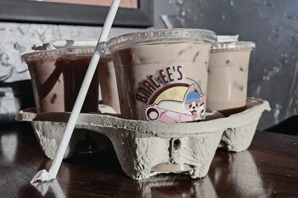 A photo of several plastic beverage cups in a cardboard holder. The cups have a logo of a dog driving a car and say &quot;Barc-ee&#x27;s&quot;