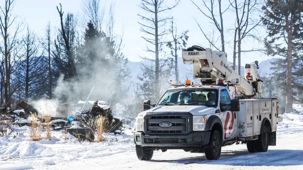 An electric utility truck drives down a street after a wildfire.