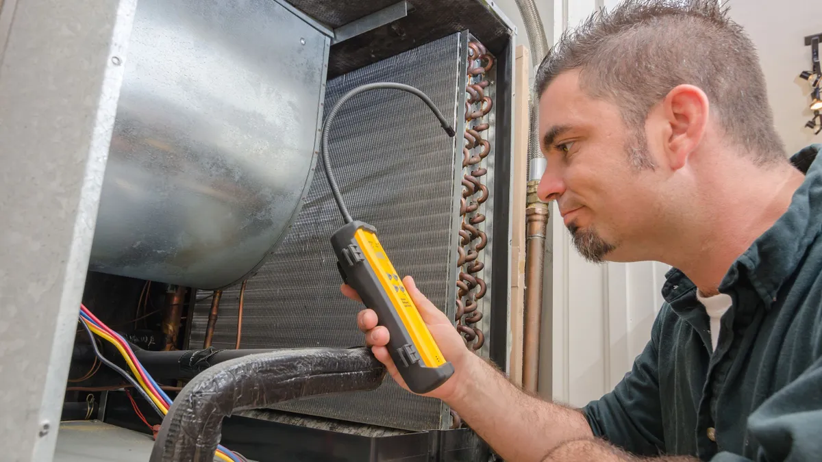 An HVAC technician searches for a refrigerant leak on an evaporation coil.