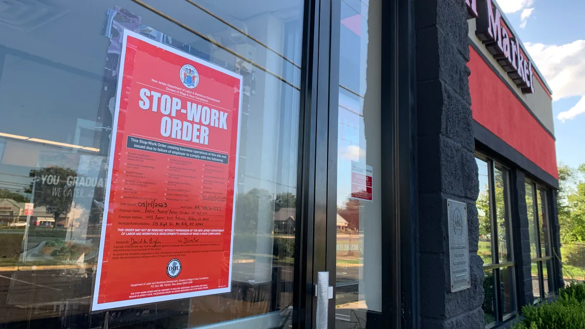 A red stop-work order is taped to a Boston Market door.