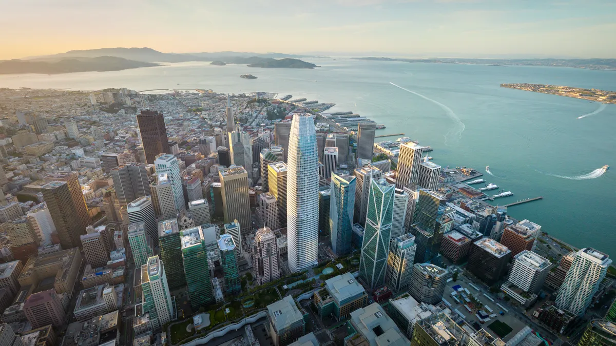 Aerial panoramic cityscape view of San Francisco skyline with high rises and water to the right.