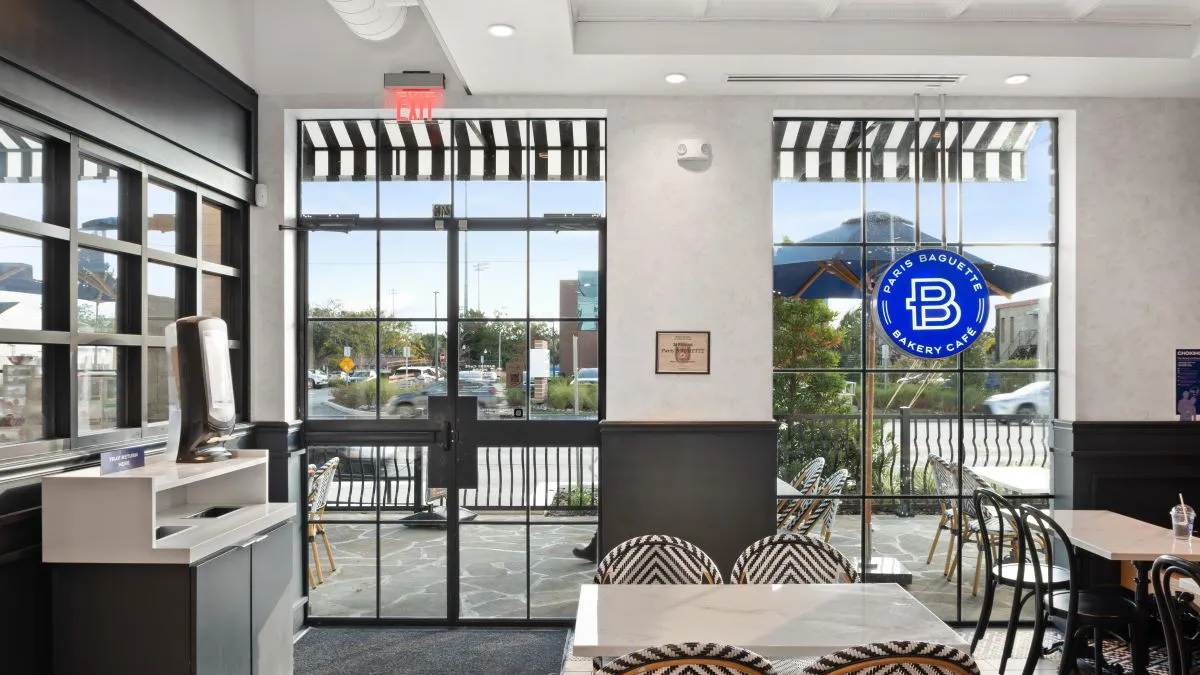 An image of the inside of a Paris Baguette with tables and chairs.